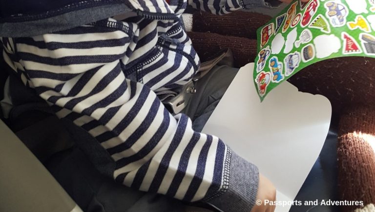 Awesome Tips For Flying With Babies and Toddlers - Toddler playing with stickers on an airplane