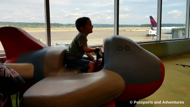 Awesome Tips For Flying With Babies and Toddlers - A toddler playing on a toy airplane in Portland airport children's play area