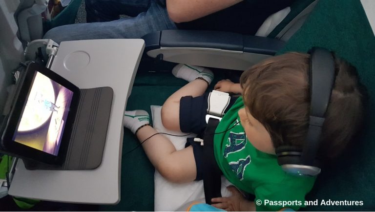 Awesome Tips For Flying With Babies and Toddlers - A toddler on an airplane watching a tablet