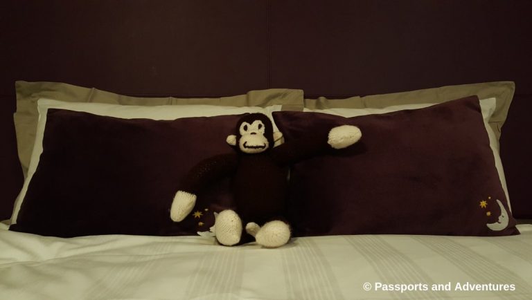 Awesome Tips For Flying With Babies and Toddlers - A Curious George monkey teddy bear sitting on a hotel bed