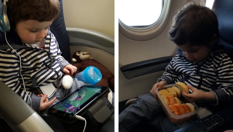 Awesome Tips For Flying With Babies and Toddlers - A Toddler eating snacks and watching a tablet on a plane