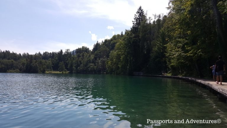 People walking along the boardwalks along the side of Lake Bled