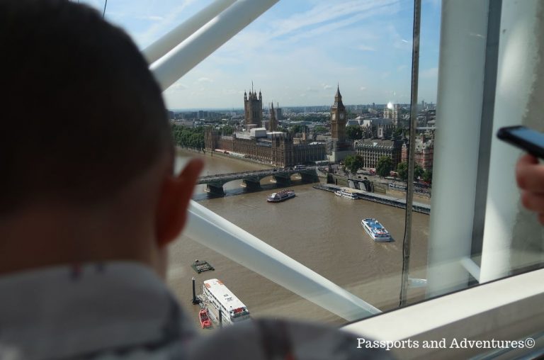 A picture of a little boy looking out the window of one of the capsules in the London Eye towards Big Ben and the Houses of Parliament