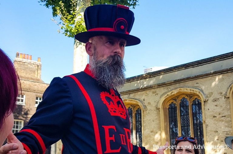 A Yeoman warder in his blue and red uniform giving a talk during a Beefeater tour at the Tower of London