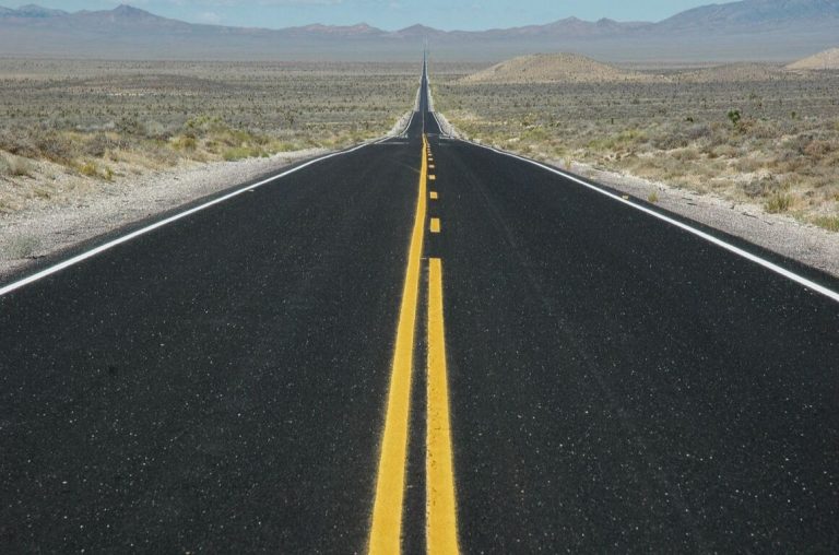 A picture of a long road of black tarmac stretching into the horizon