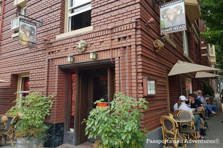 A brown-bricked pub/bar building with tables and chairs outside with people sitting on them in Portland, Oregon