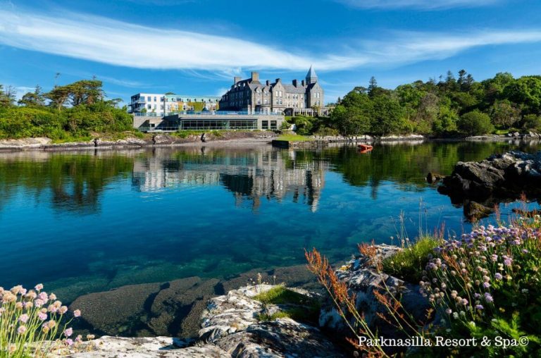 A picture of the Parknasilla Resort Hotel exterior from across a blue lake