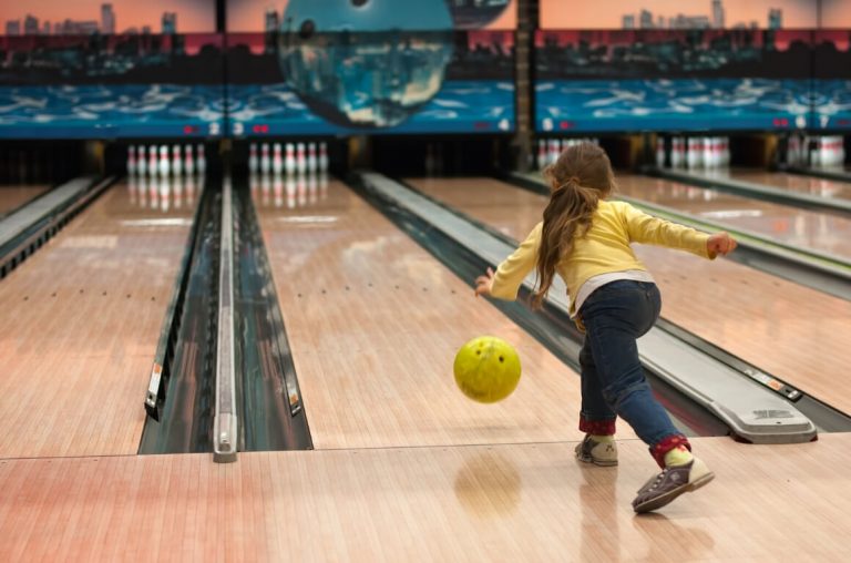 A picture of a young girl bowling in a bowling alley