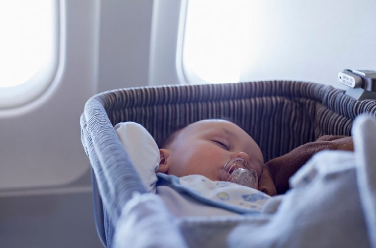 A baby asleep in an airplane bassinet