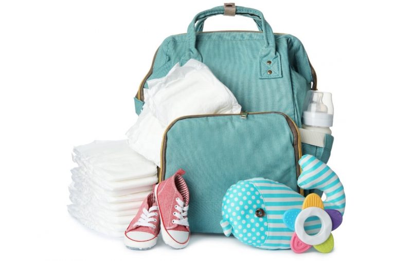 A picture of a green backpack diaper bag with a baby toy, diapers, bottle and pink baby shoes